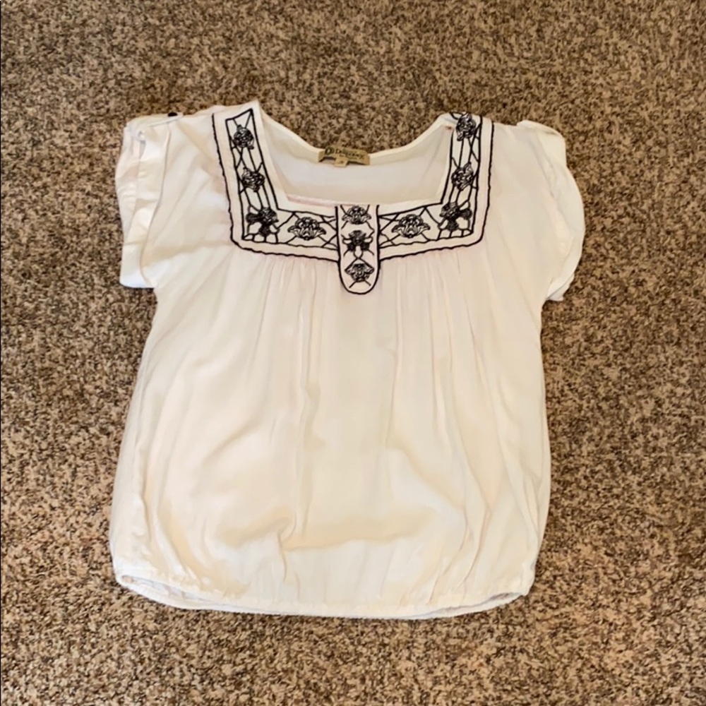 White blouse with navy/black stitching.